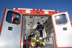 Paramedics with man on stretcher in ambulance, low angle view