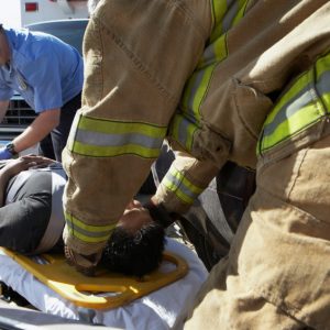 Firefighter and paramedics taking victim out of crashed car