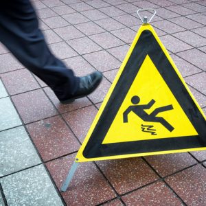 Man walking past a slippery floor sign