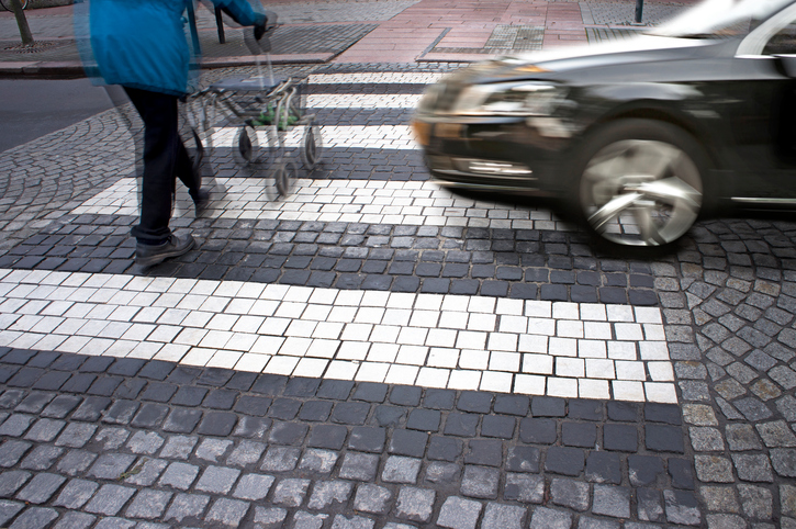 Senior citizen crossing street with fast car approaching