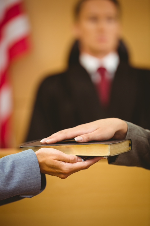 Witness swearing on the bible telling the truth in the court room