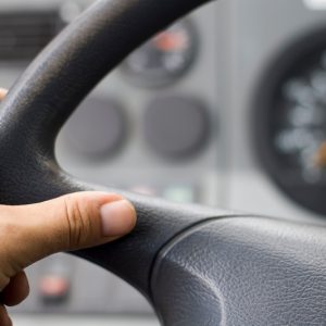 man driving with his hand on the wheel a truck