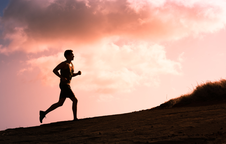 Fitness male running outdoors during sunset.