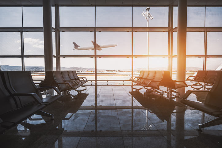 Window at airport overlooking plane flying by.