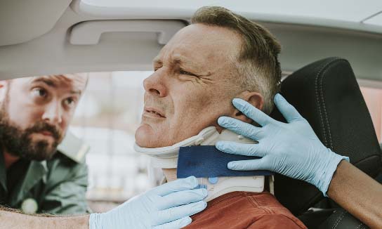 Injured man in a neck brace being assisted by paramedics.