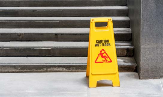 Wet floor sign sitting next to a flight of stairs.