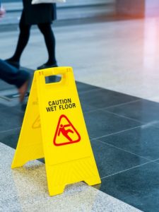 Yellow wet floor sign propped in the middle with people walking around it.