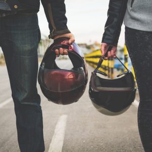 Motorcycle couple holding helmets in hands on the road