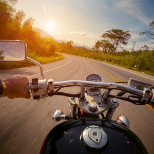 Driver riding motorcycle on the empty asphalt road