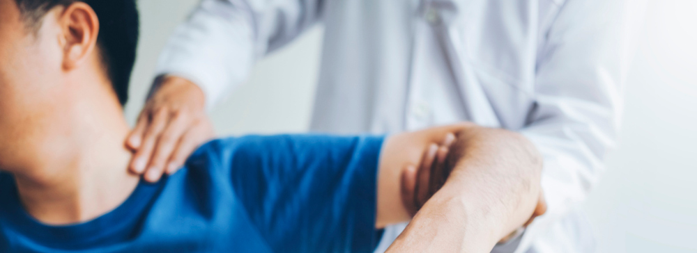 Doctor physically examining a male patient's arm and shoulder