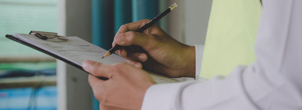 An investigator writing on a clipboard while inspecting a building