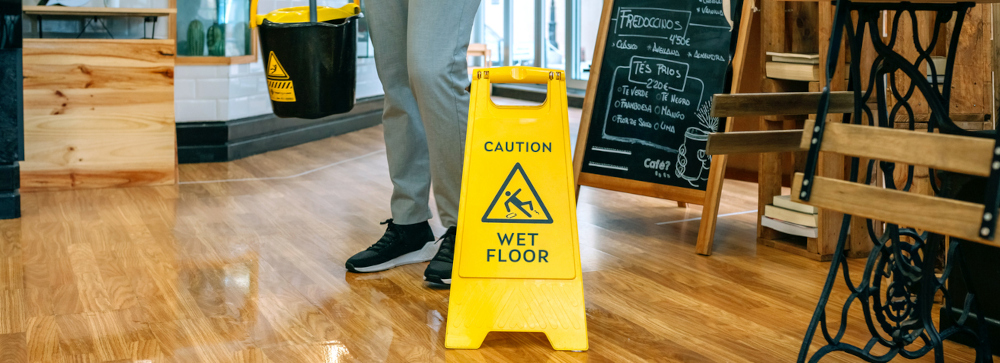 A slip and fall sign on a wet wooden floor inside a restaurant