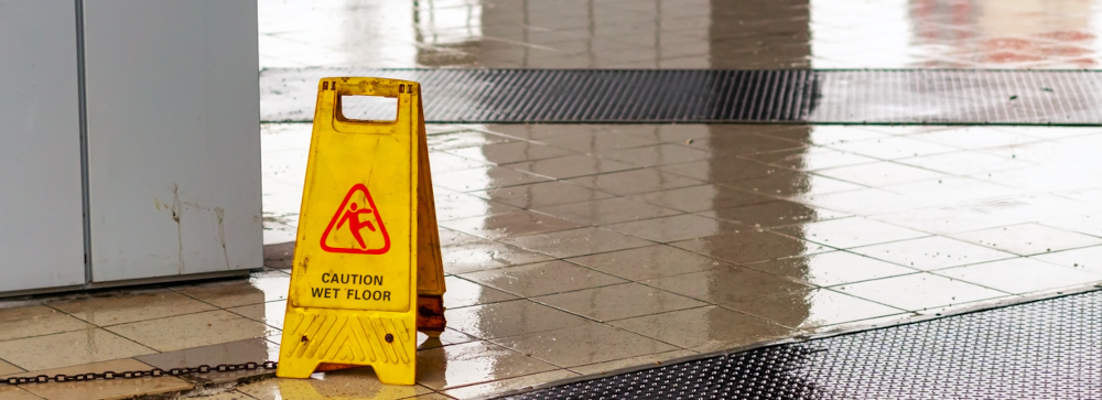 A yellow caution sign in the entryway of a building with water on the floor