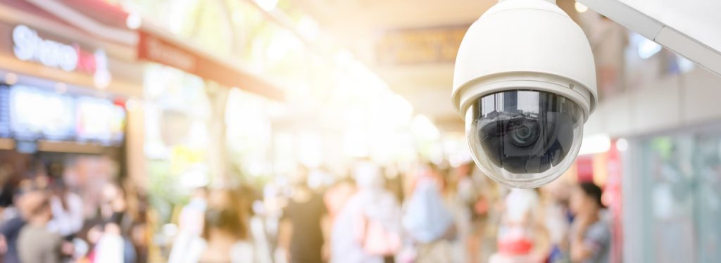 A surveillance camera outside a business in a crowded shopping district