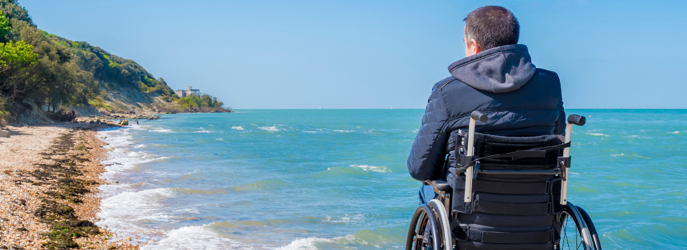 Back of disabled man in wheelchair at beach