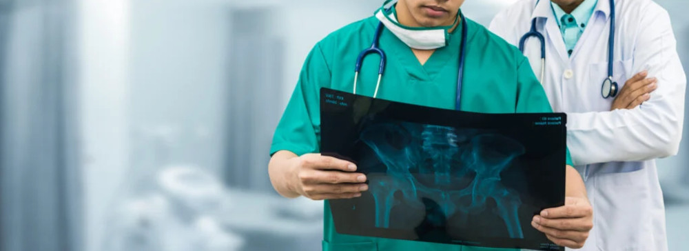 Dos médicos en un hospital revisando una radiografía de la cadera de un paciente