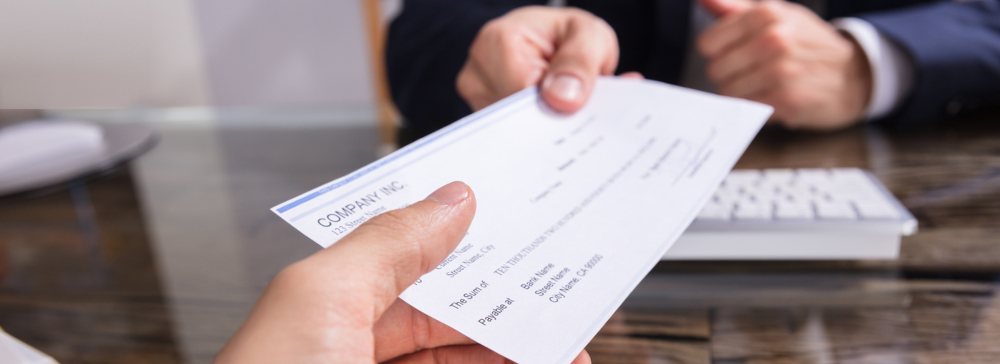 Close-up of a Man from a first person perspective handing the photographer a check