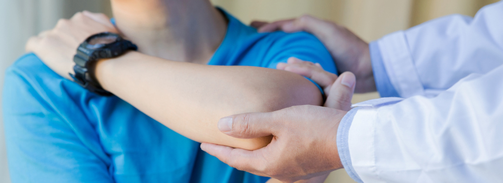 A doctor helping adjust the shoulder and arm of an injured patient