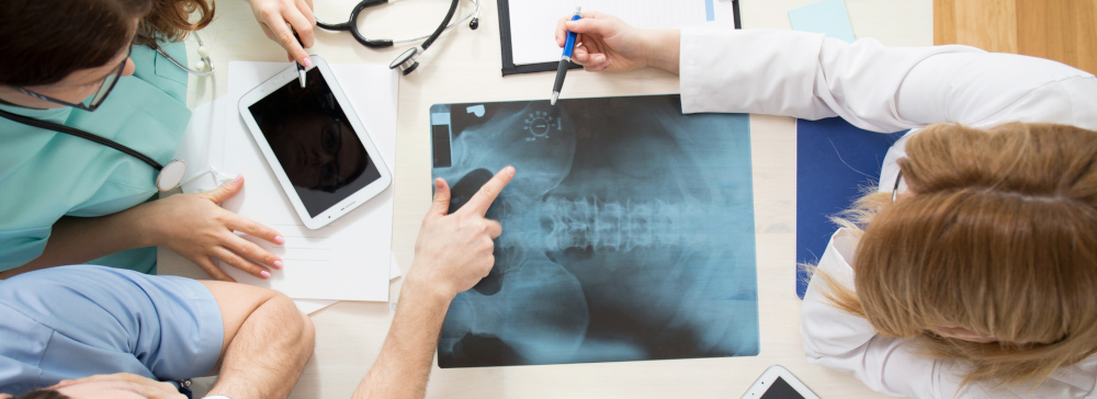 Doctors sitting around a table and interpreting an xray of a hip injury