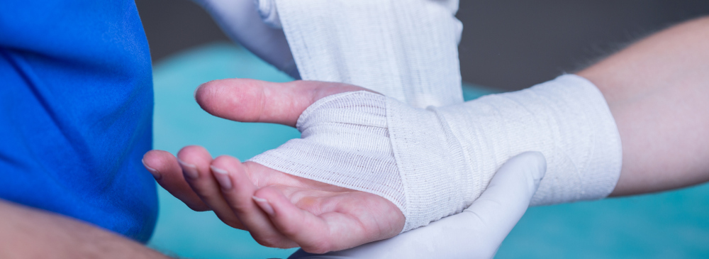 A close-up of a doctor bandaging a person's hand and wrist injury