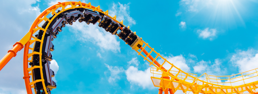 A roller coaster high in the summer sky at a theme park