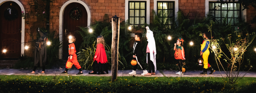 Group of children trick or treating in front of a house at night on Halloween