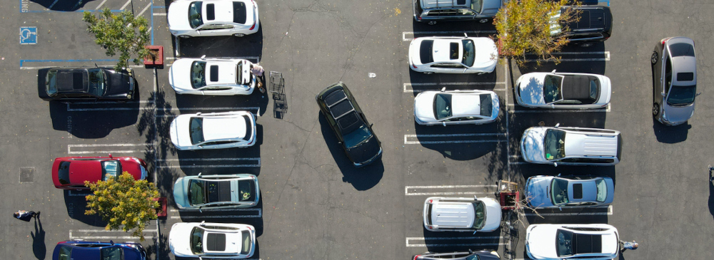 Aerial view of a parking lot with parked and driving cars