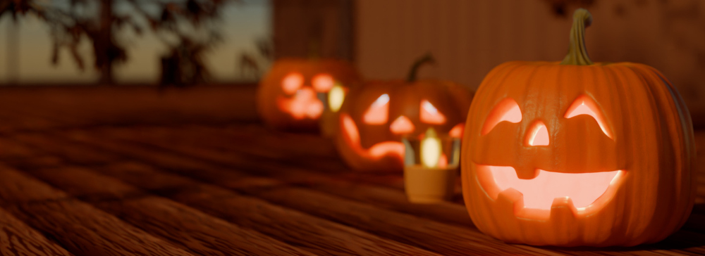 Three carved pumpkins sitting on a porch on Halloween